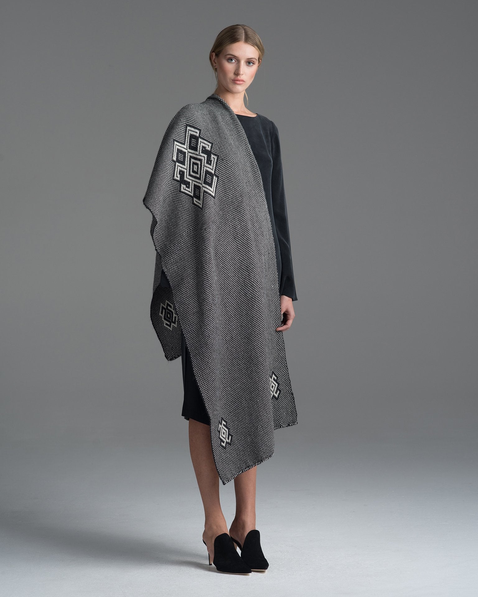 Model wearing a charcoal and ivory Araña shawl with a geometric pattern