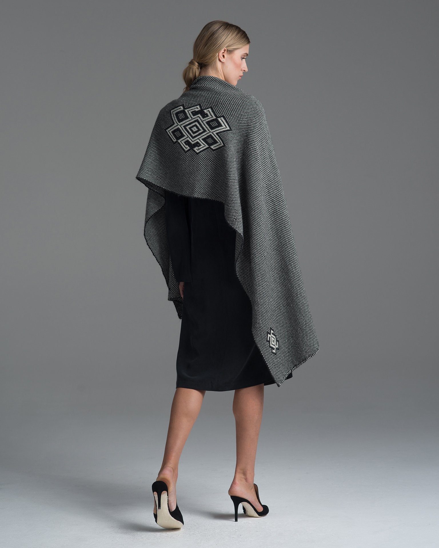 Model wearing a charcoal and ivory Araña shawl, showcasing its design and texture.