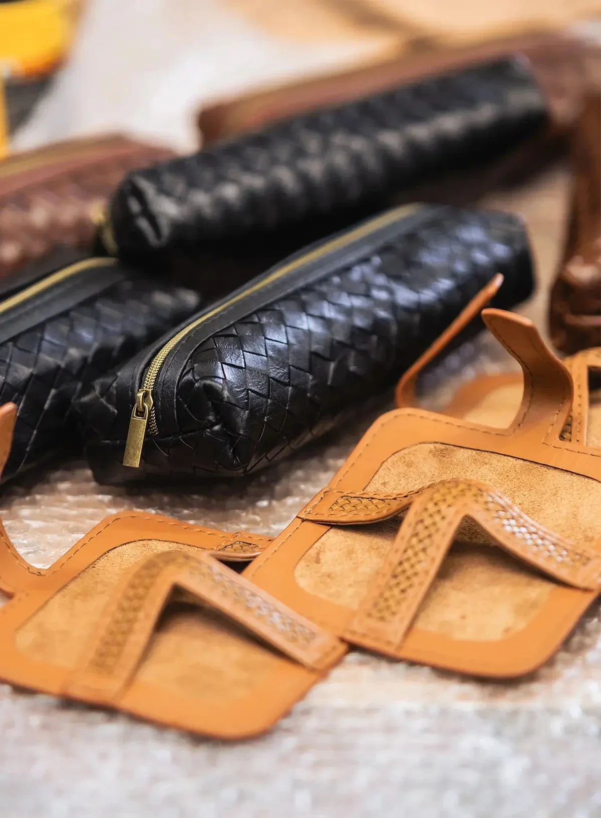 Close-up of leather products including a black woven pencil cases  and coasters in factory